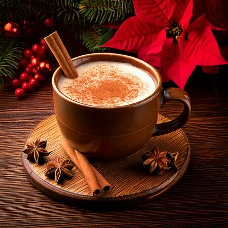 Eine rustikale Tasse Champurrado auf einem Holztisch, dekoriert mit Zimtstangen, Anis und kleinen Weihnachtssternen.